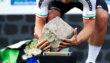 A rider stoops to pick up the cobblestone trophy as Paris-Roubaix winner