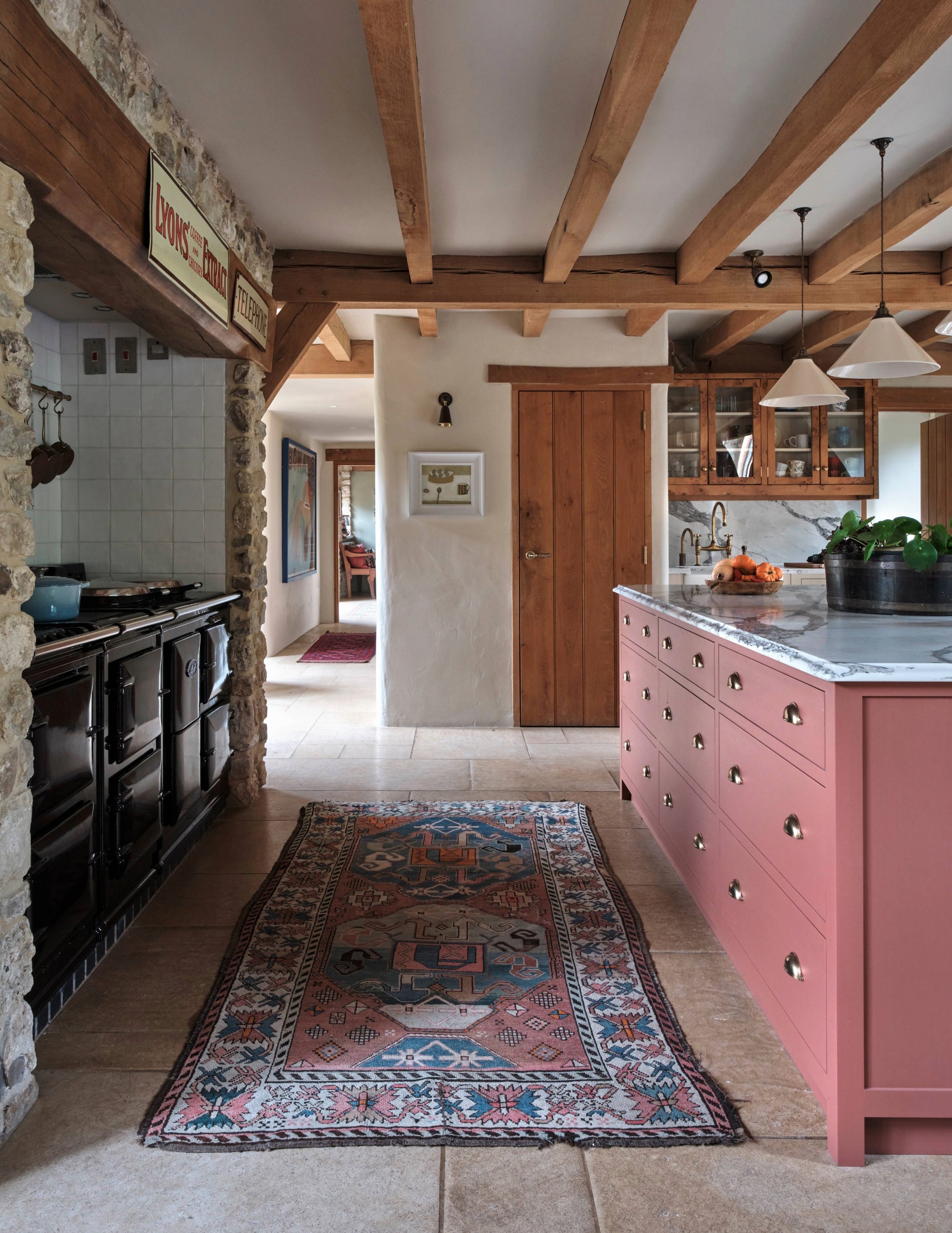 a farmhouse style kitchen with stone floor exposed beams and colourful cabinetry