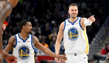 A man wearing a black San Francisco Giants cap and gray baseball jersey looks intently to his right against a dark, blurred background.