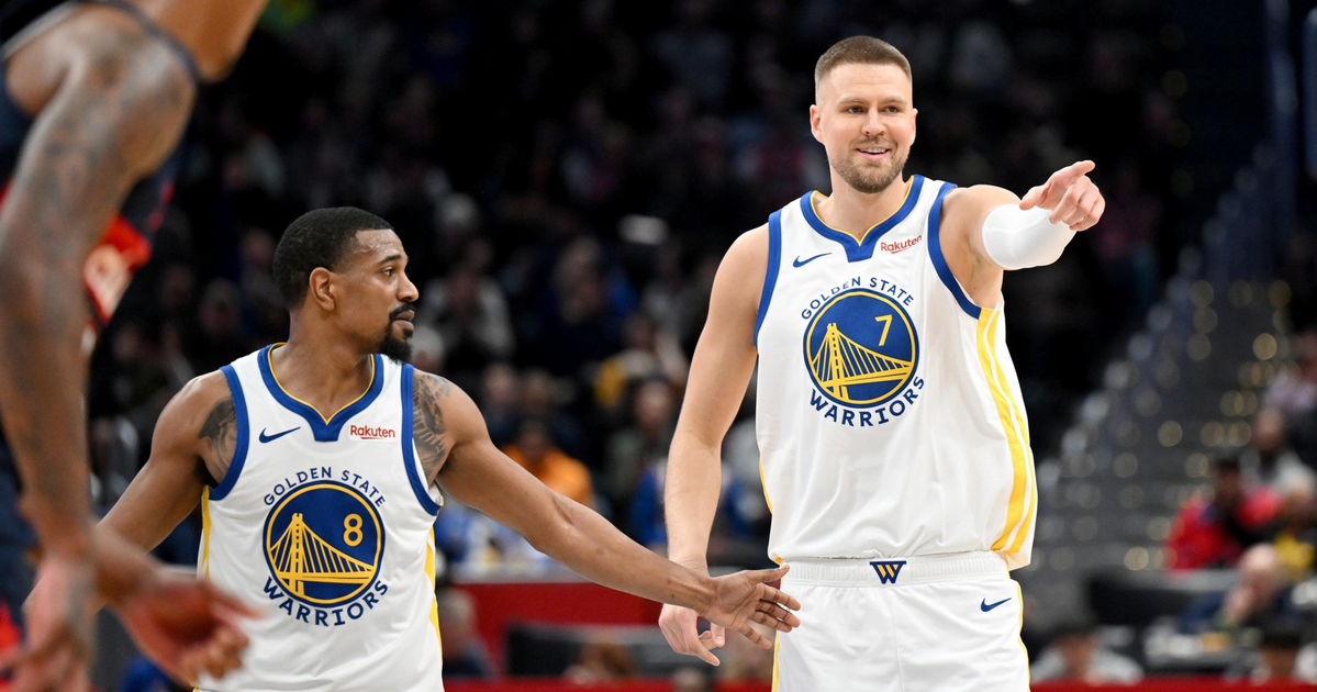 A man wearing a black San Francisco Giants cap and gray baseball jersey looks intently to his right against a dark, blurred background.