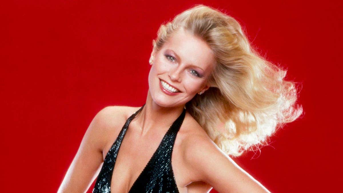 Cheryl Ladd in a glamorous pose against a red backdrop.