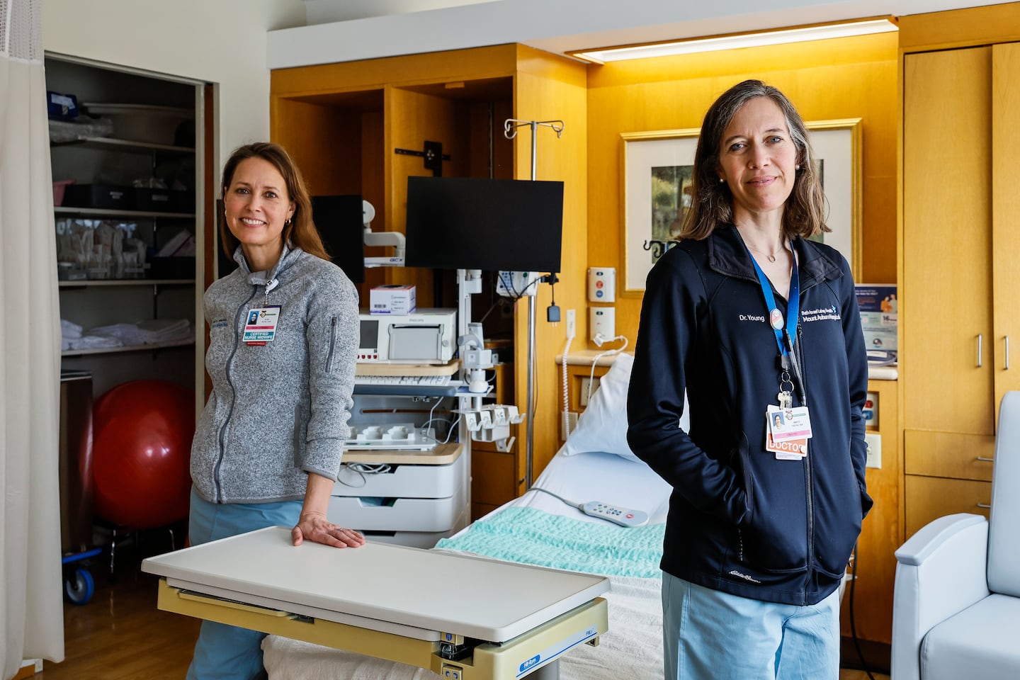 Certified nurse-midwife Julie Mann (left) and Dr. Brett Young posed for a portrait inside a labor and delivery room at Mount Auburn Hospital in Cambridge.