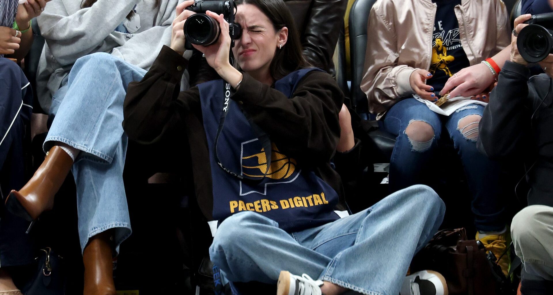 INDIANAPOLIS, INDIANA - MARCH 25: Caitlin Clark of the Indiana Fever sits on the baseline and makes photographs during the Indiana Pacers game against the Los Angeles Lakers at Gainbridge Fieldhouse on March 25, 2026 in Indianapolis, Indiana.