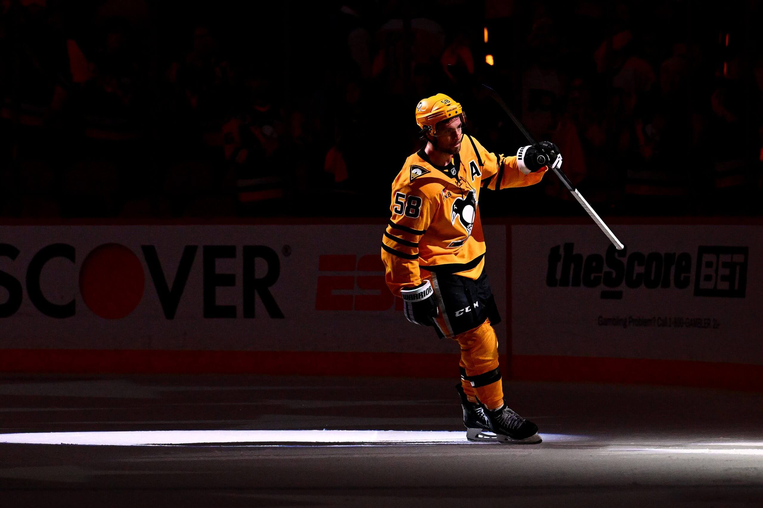 Kris Letang skates out in a dark arena with a spotlight on him after a Penguins game.