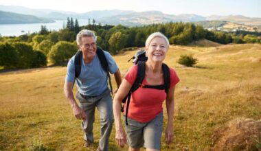 Portrait Of Senior Couple Climbing Hill On Hike Through Countryside In Lake District UK Together