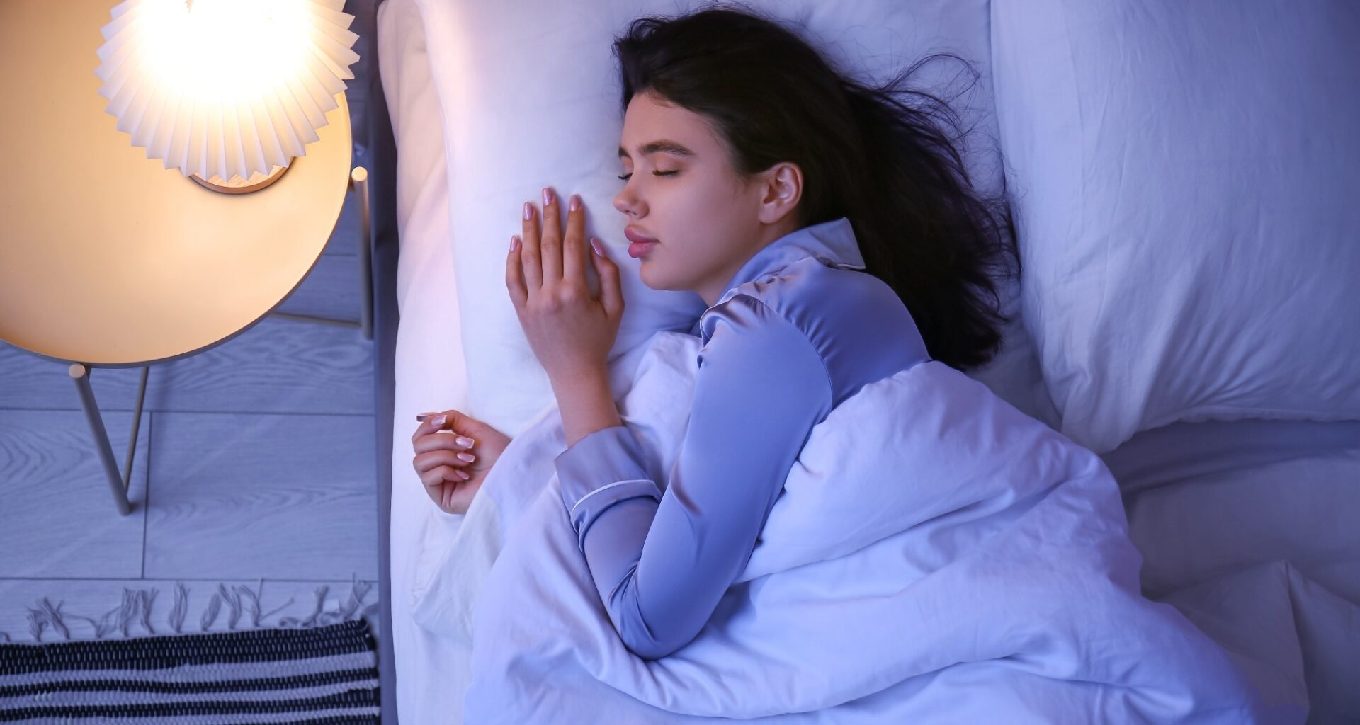 Young woman sleeping in bedroom at night, top view