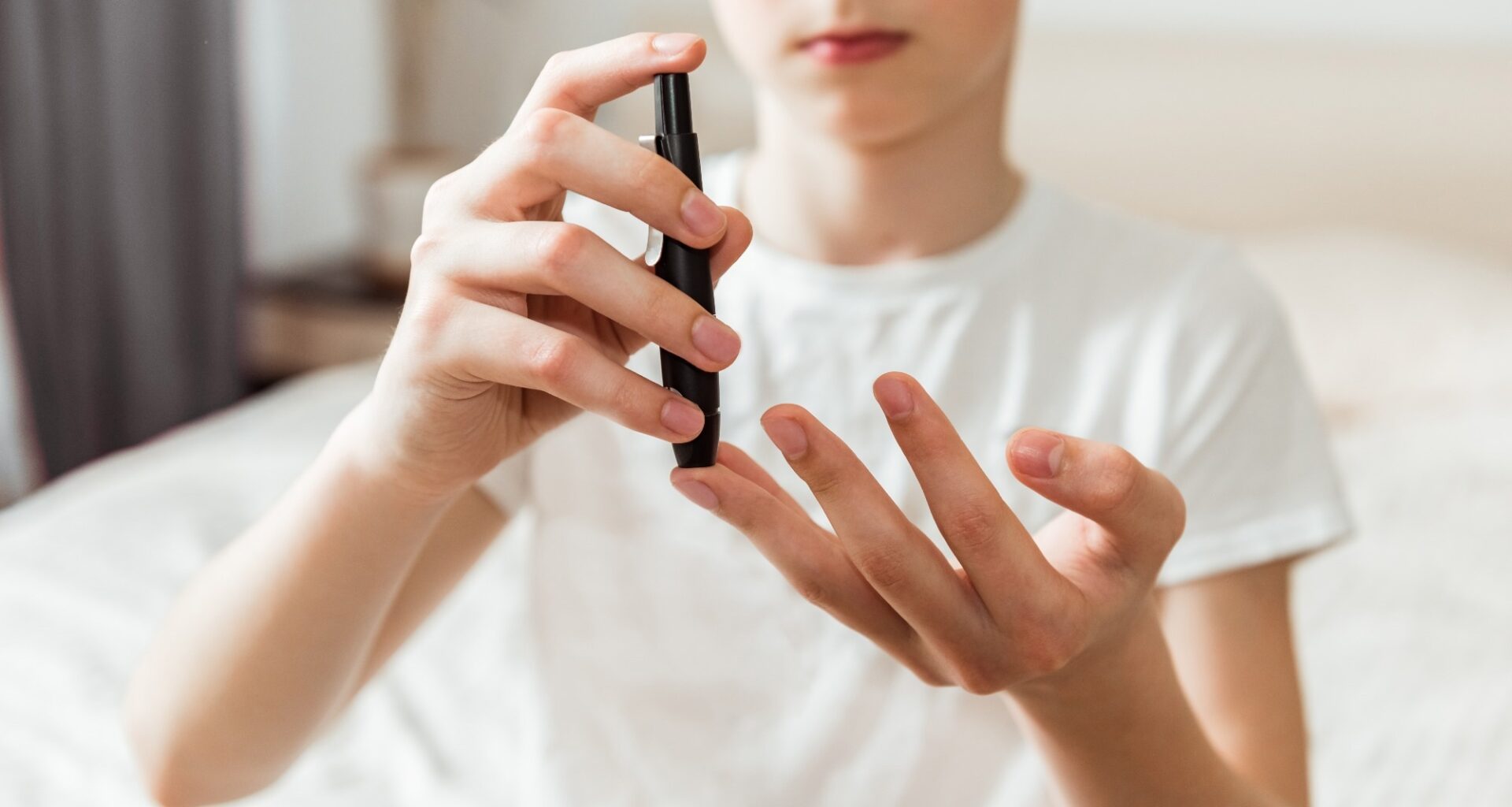 Teen boy takes a blood sample for diabetes with lancet pen. Problems of diabetes and insulin resistance in childhood