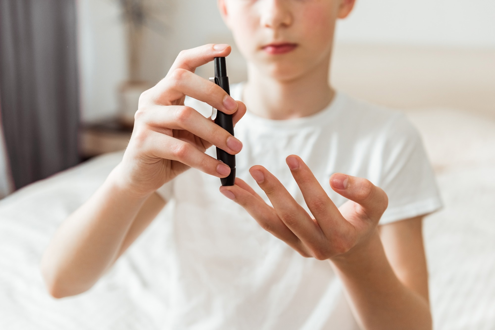 Teen boy takes a blood sample for diabetes with lancet pen. Problems of diabetes and insulin resistance in childhood
