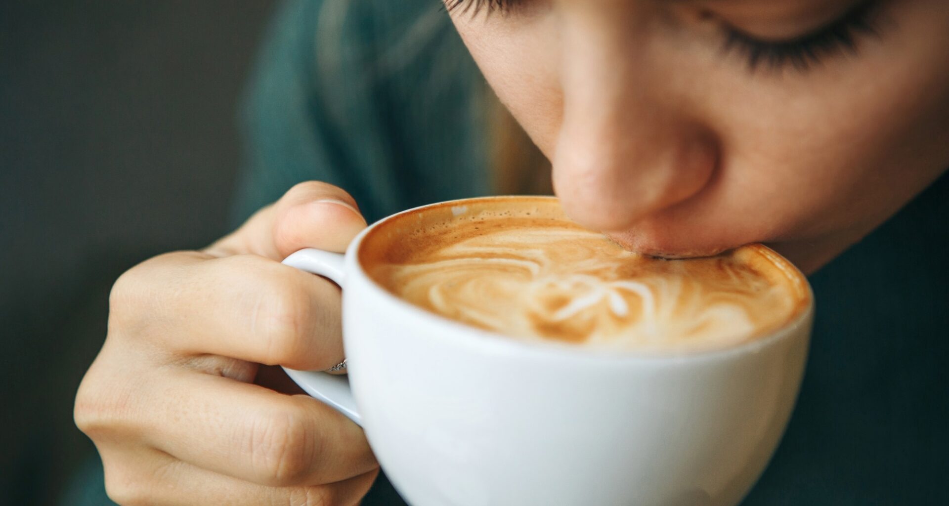 Close up girl is drinking coffee. She enjoys her morning cappuccino or flat white.
