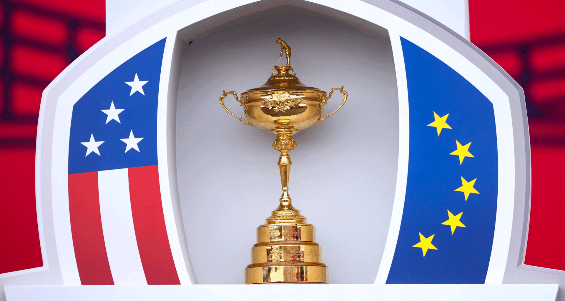 The Ryder Cup sits in between an American flag pattern (left) and a European flag pattern (right)