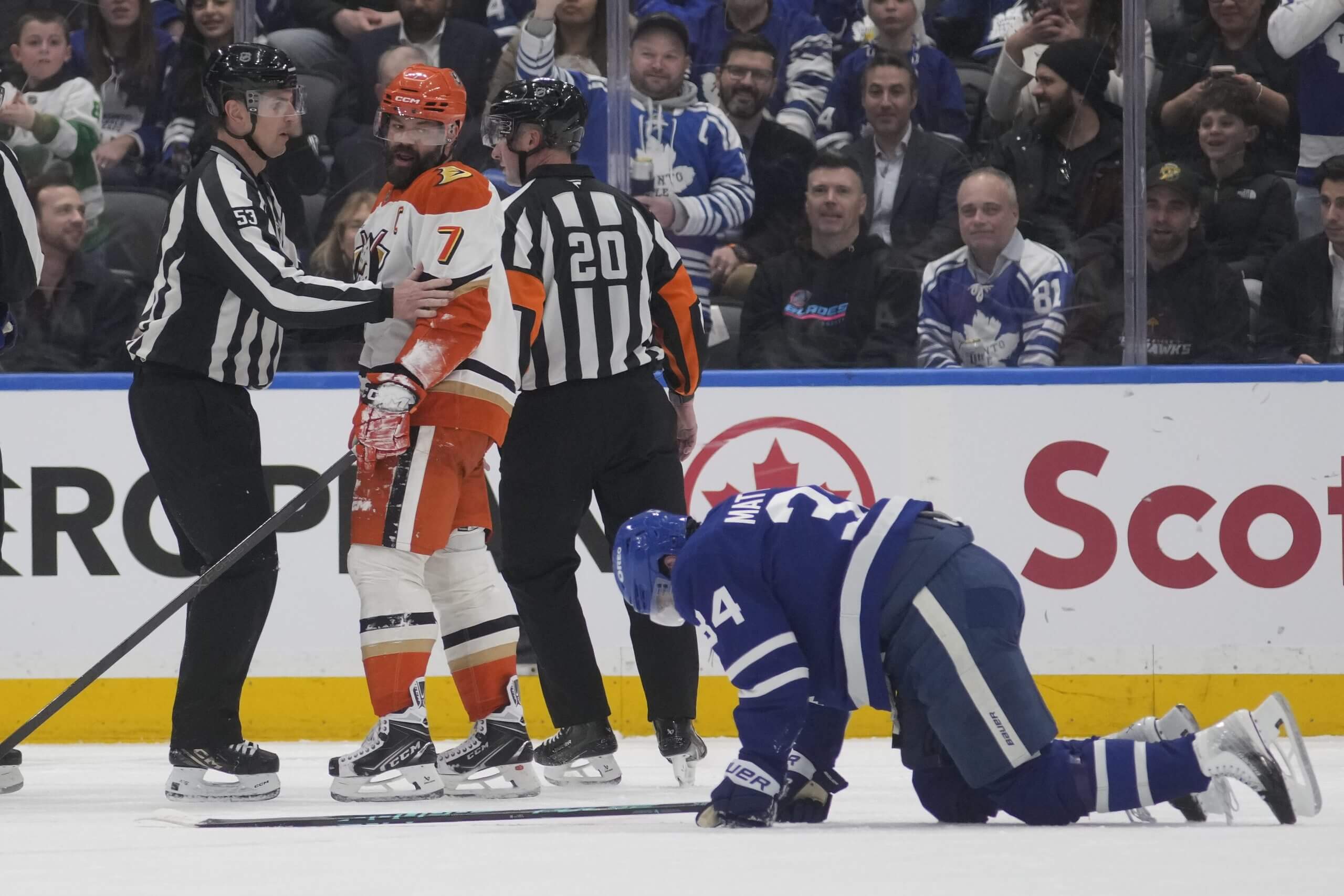 Auston Matthews rests on his hands and knees on the ice with Anaheim's Radko Gudas being moved away by referees.
