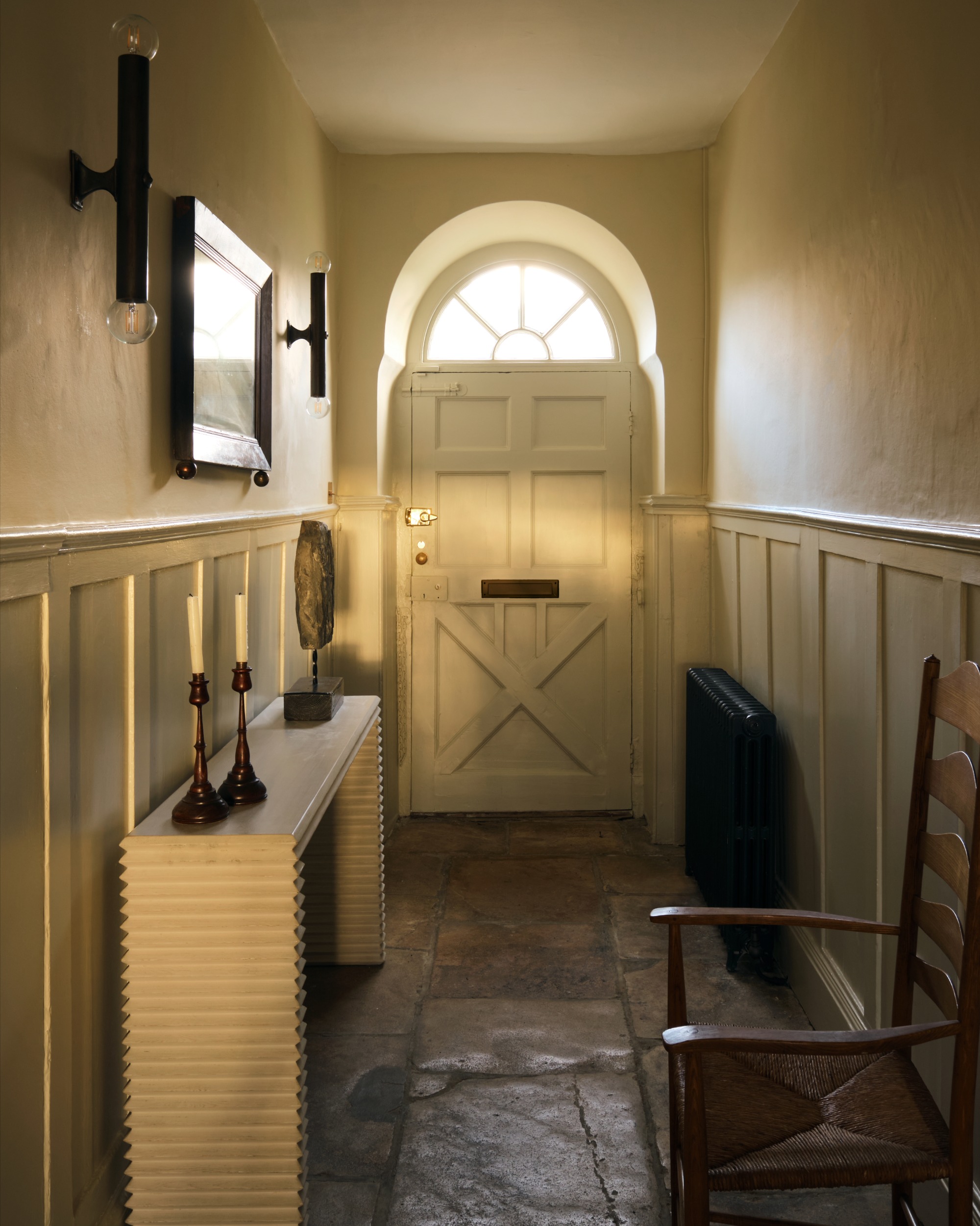 a farmhouse entryway with stone floors and wainscoting