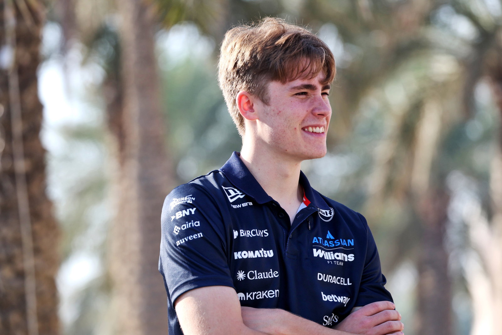Luke Browning smiling with his arms crossed in his Williams shirt