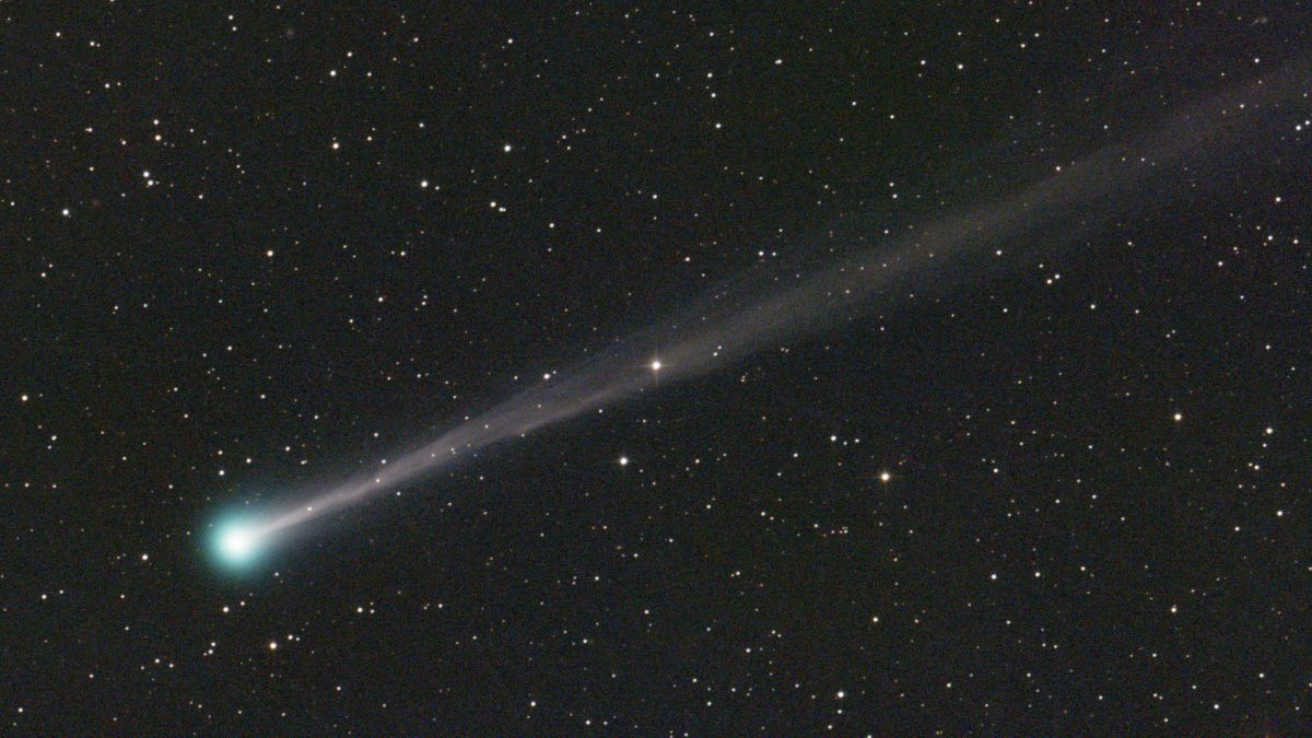 a comet with a long tail and a green blue head.