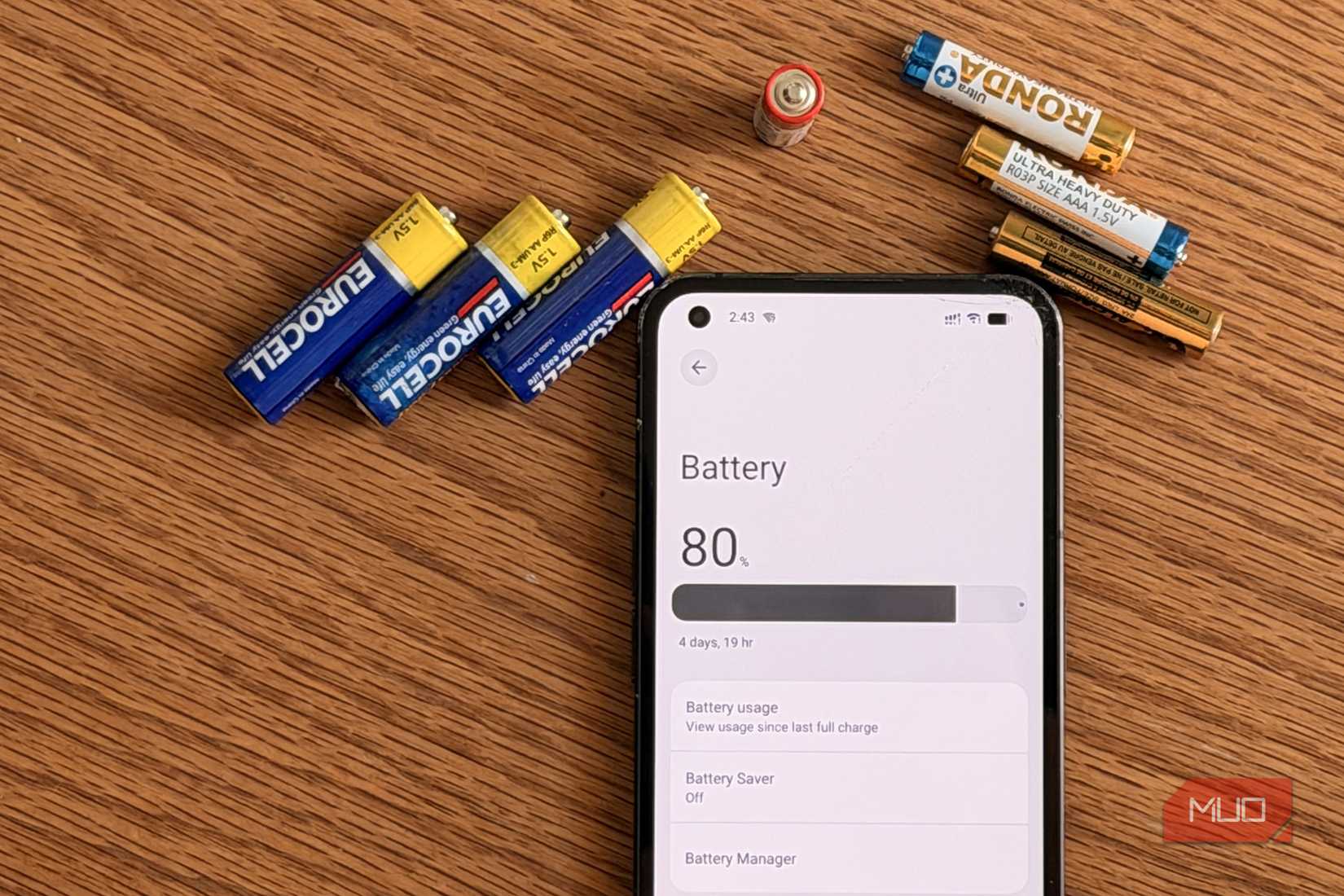 A group of AA batteries next to an Android phone showing the battery charge