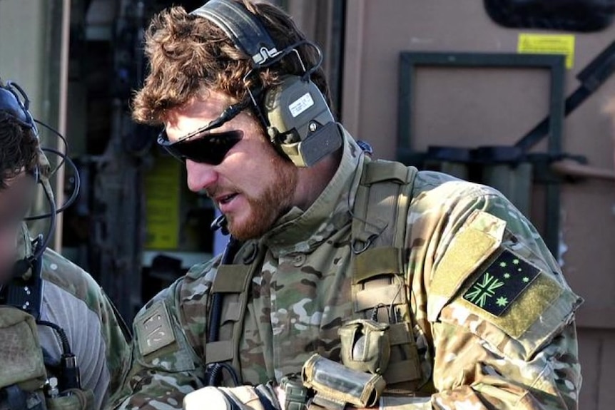 a man dressed in army combat gear wearing aviator glasses