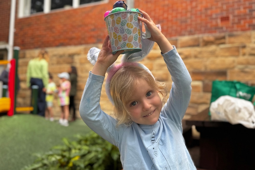 A girl holding a bucket of Easter eggs.
