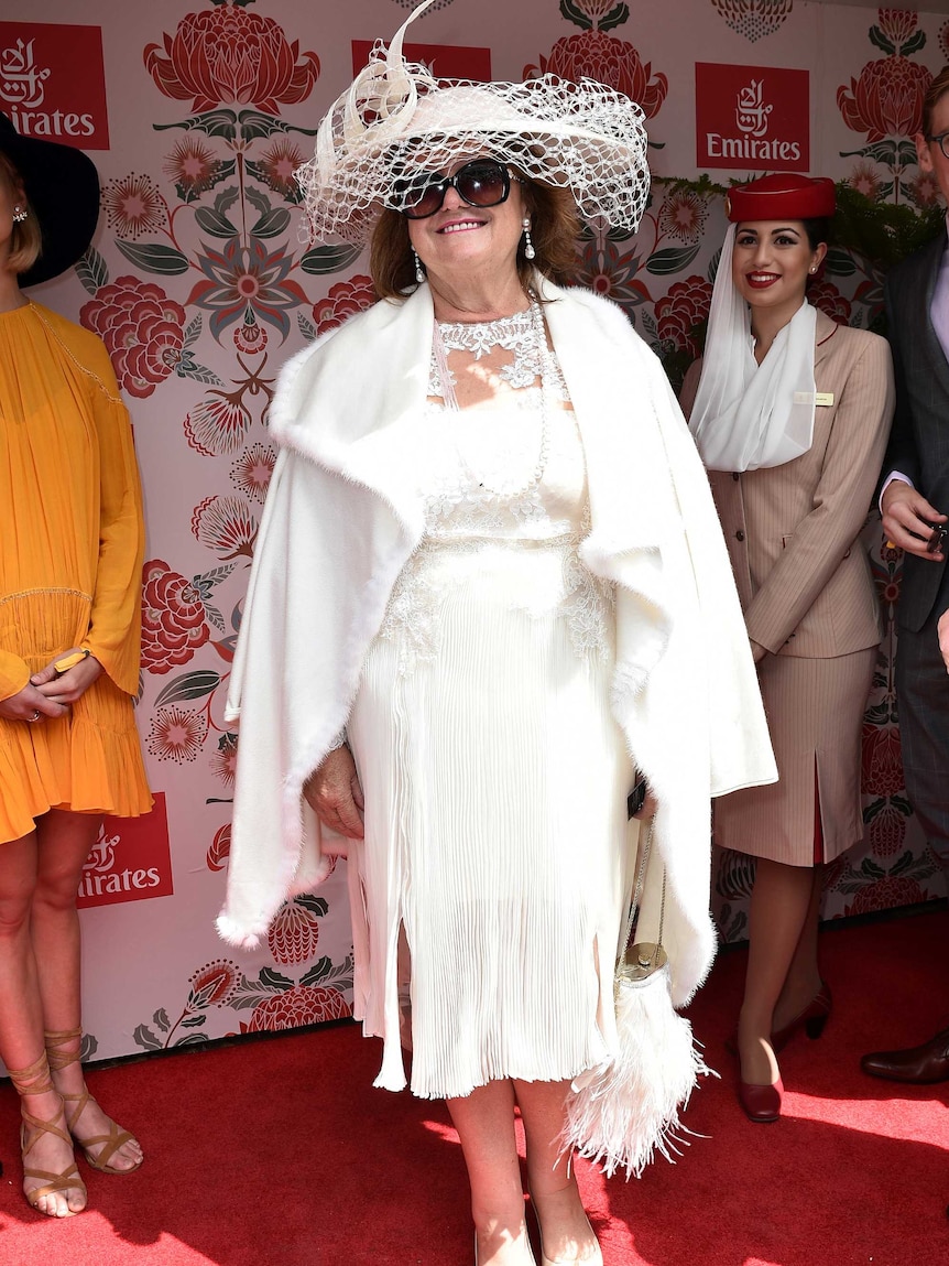 A woman wears a white outfit with a matching wide brimmed hat
