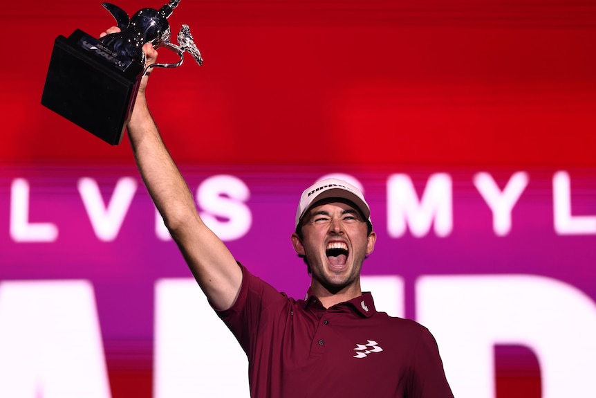 Elvis Smylie holds a trophy above his head and yells in delight