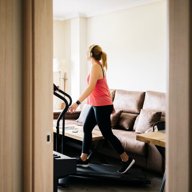 Woman exercising on treadmill at home wearing headphones Woman exercising on treadmill at home wearing headphones