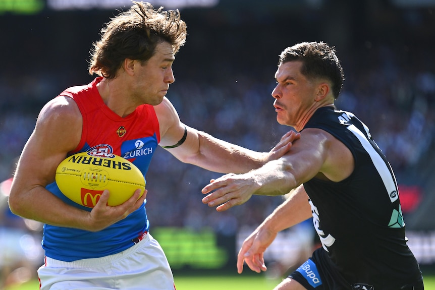 Tom Sparrow of the Demons fends off a tackle by Ben Ainsworth of the Blues during a 2026 AFL match.