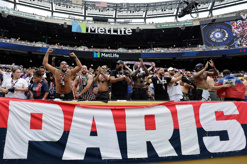 PGS fans cheer in the crowd in front of a giant flag which reads 'PARIS'.