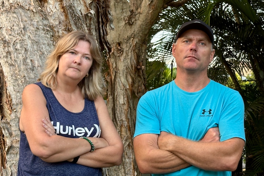 man and woman standing arms crossed looking stern