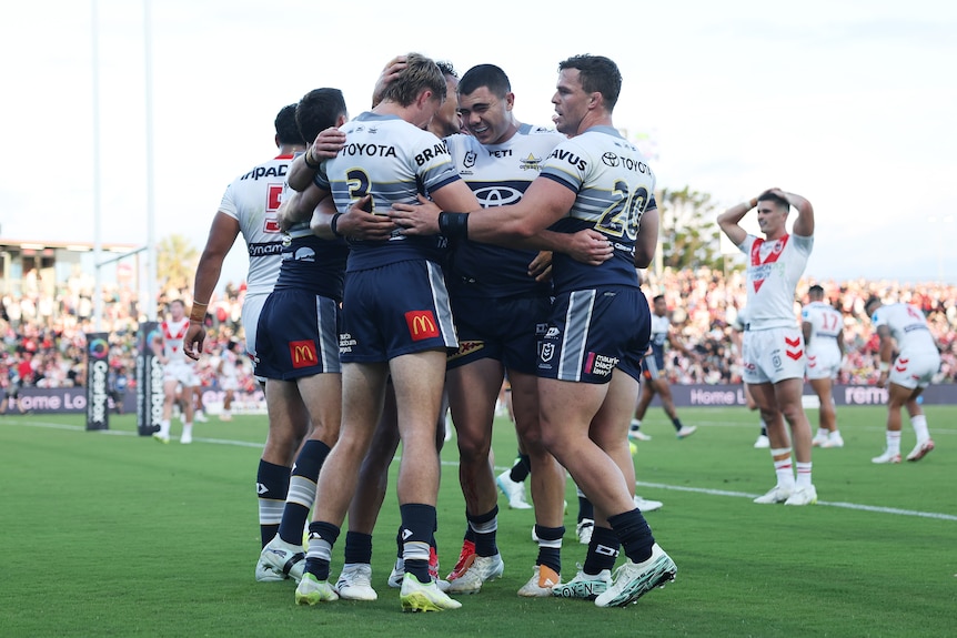 A group of rugby league players huddle in celebration