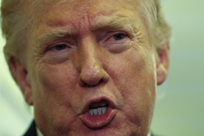 A close up of Donald Trump's face as he speaks to reporters.