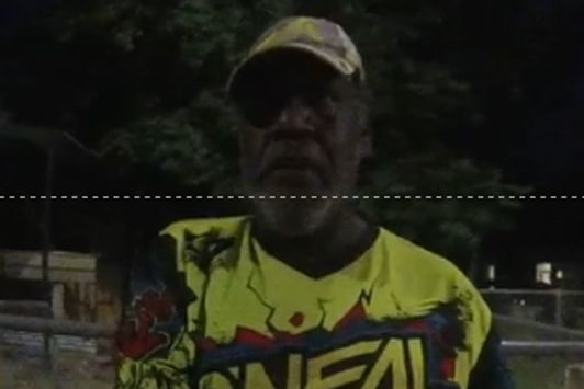 A dark low-res image of an Aboriginal man, wearing a bright yellow shirt and yellow cap.