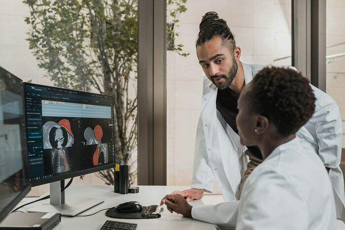 Two medical professionals examining hospital scan images on a computer, highlighting hidden hospital truths and concerns.