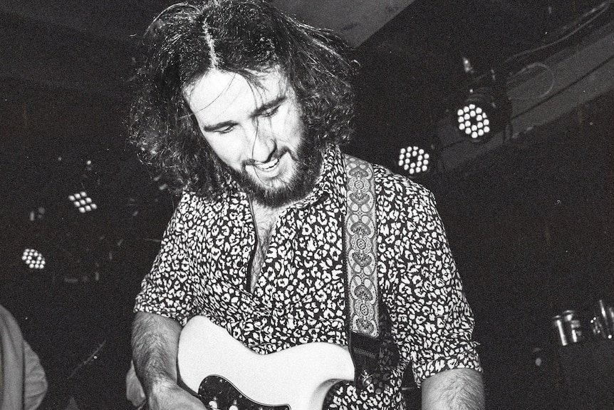 black and white photo of a man playing a guitar. 