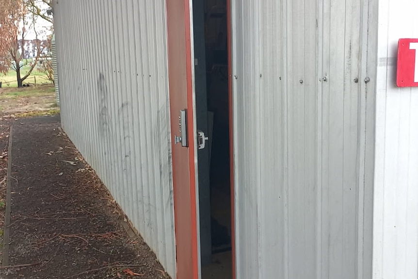 Image of a white shed's door slightly ajar. 