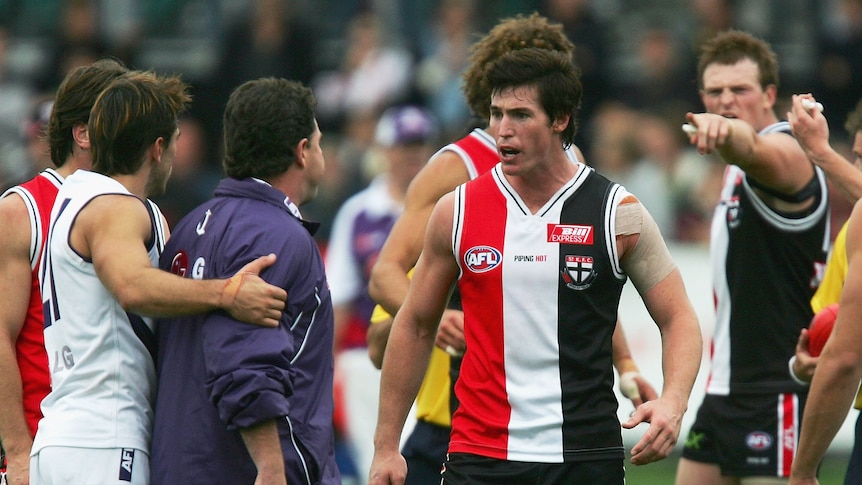 A Fremantle AFL player holds his coach back as the St Kilda captain confrtons him and a Saints player points in the background.