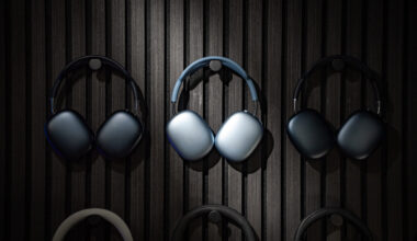 Apple AirPods Max 2 headphones hanging on a wall alongside two older generation AirPods Max headphones.