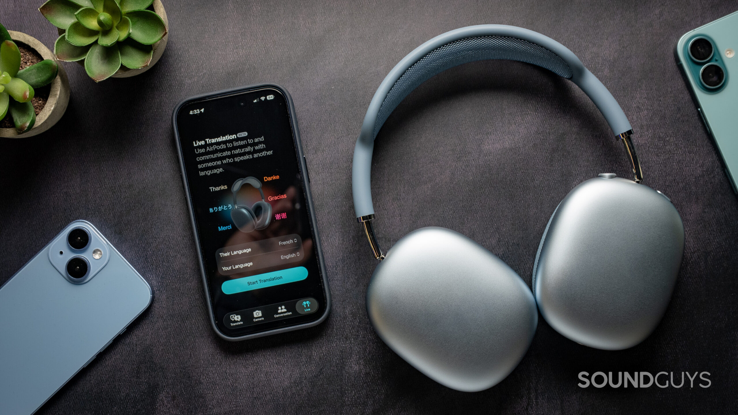 apple airpods max 2 live translation Apple AirPods Max 2 headphones on a table next to an iPhone 17 Pro showing the Live Translation feature