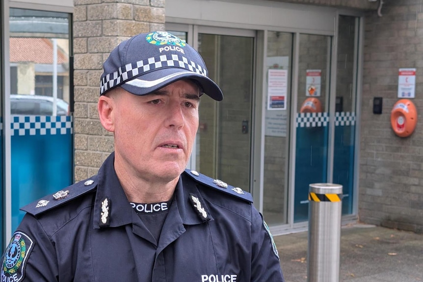 A police officer in a cap standing in front of a police station