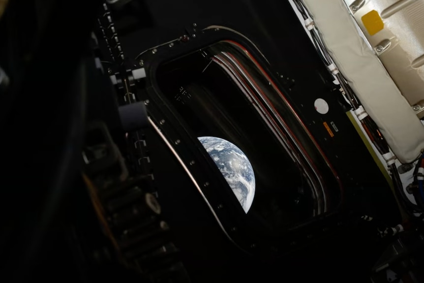 This image shows a curved slice of Earth in a space capsule window.