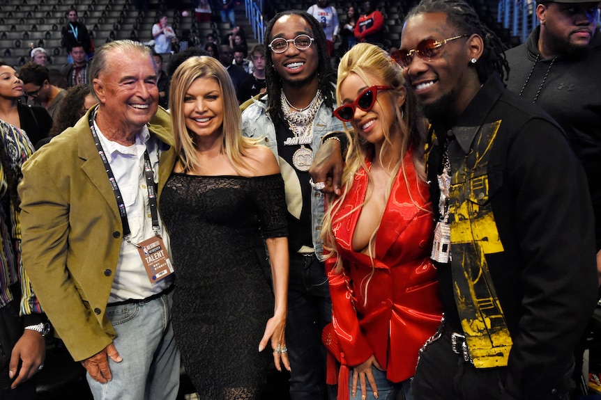 Cardi B wearing a red blazer her hand on her leg shows square shaped nails pictured with four others. 