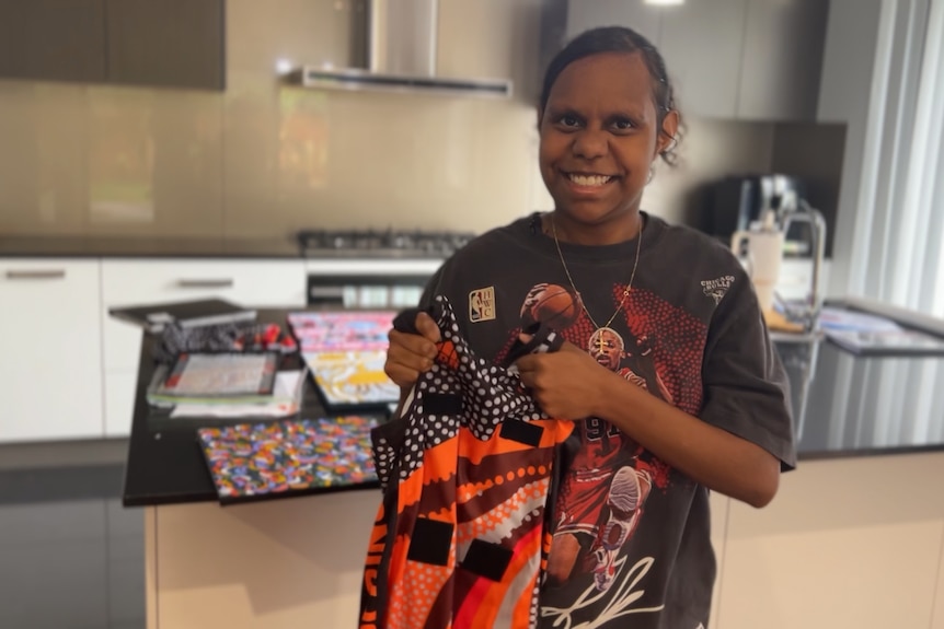 Keira holds the netball uniform she designed.