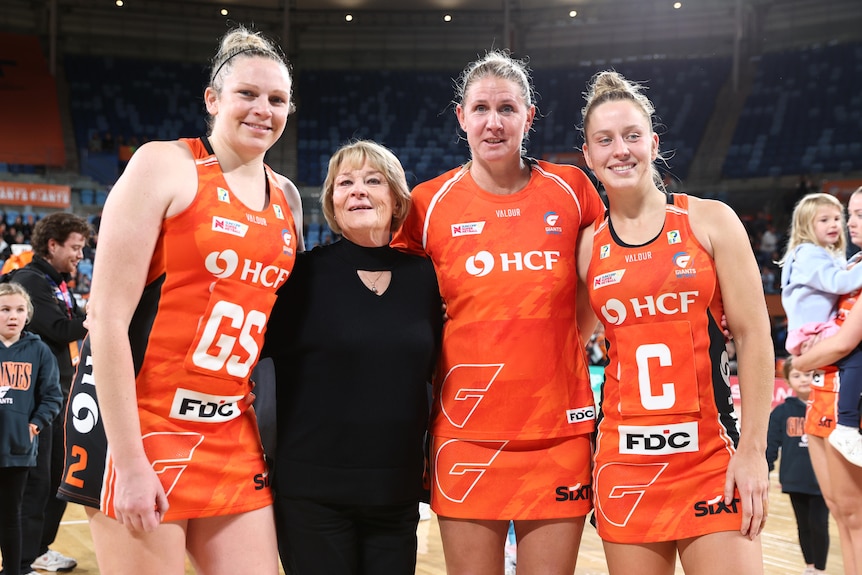 Four experienced figures from the Giants pose together after the final game of 2025