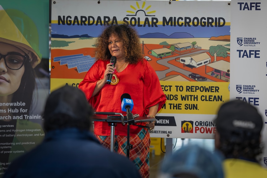Woman with curly hair hols microphone and talks to crowd