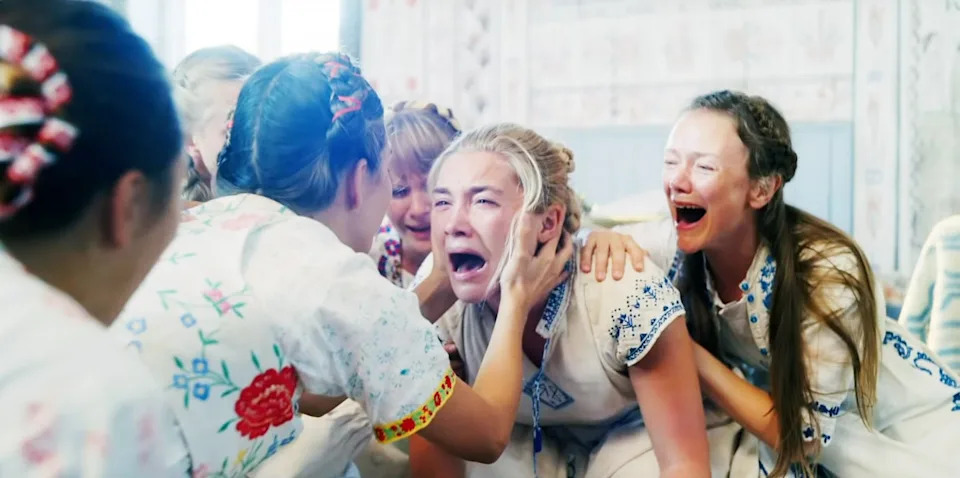 Women in traditional embroidered clothes surround a crying woman, offering support and comfort