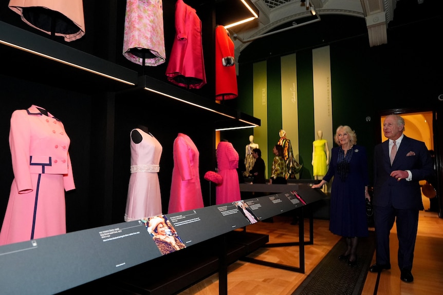 A wall of hot pink dresses and outfits with two people standing nearby