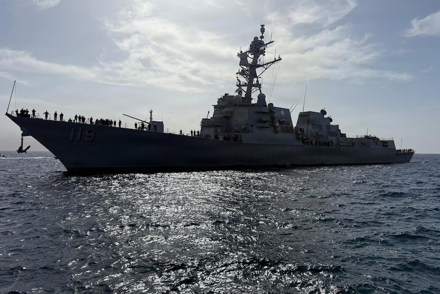 a us navy destroyer ship moving right to left in the ocean