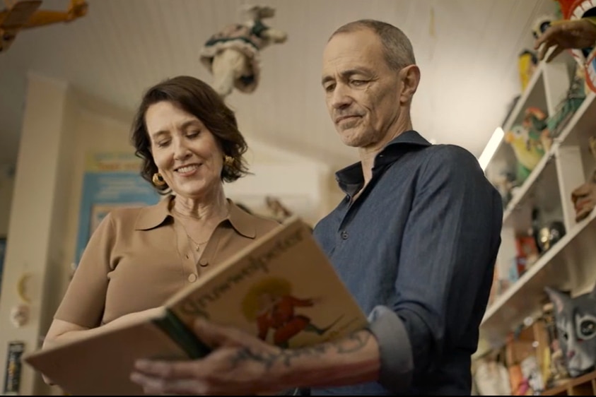 Andy Griffiths holds an old picture book open, showing it to Virginia Trioli