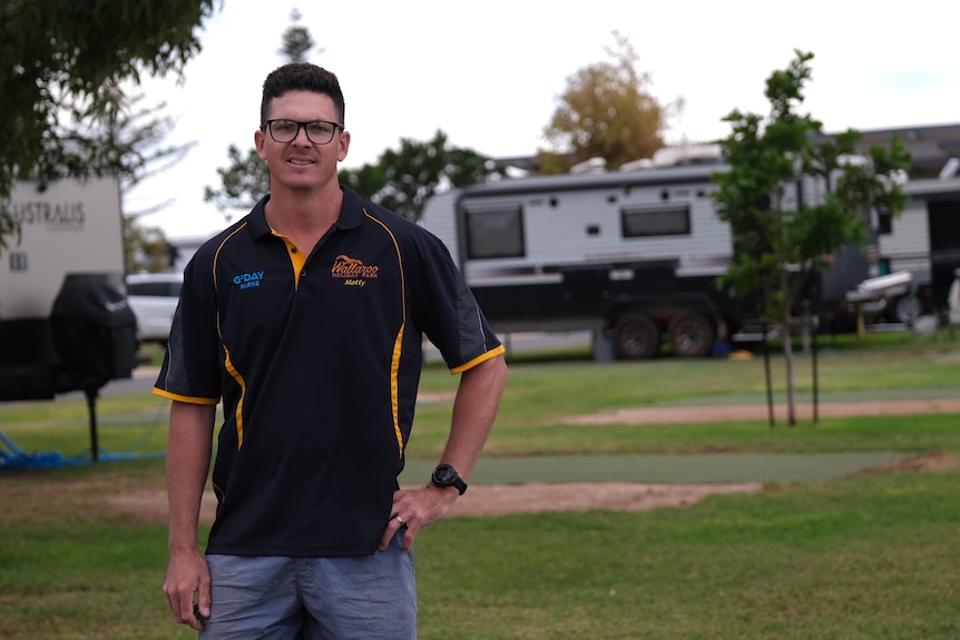 A wide shot of a man standing in front of a group of caravans. 