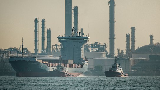 A container ship sails past an oil refinery at Bukom Island in Singapore.