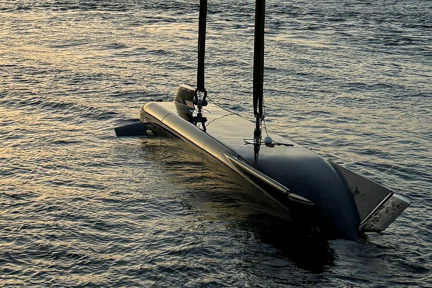 A black mini submarine looking underwater drone being lowered into the water. 