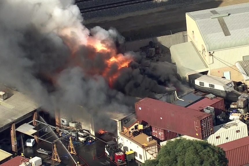 Flames can be seen billowing from a building in an industrial area.